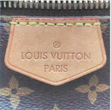 Spotting Fake Designer Bags-Close - up of a shield - shaped leather tag from a Louis Vuitton bag, embossed with "LOUIS VUITTON PARIS"