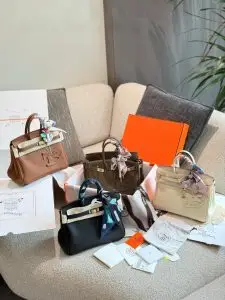 Several Hermes - inspired handbags displayed on a sofa, accompanied by orange - colored packaging boxes, dust bags, and other accessories.