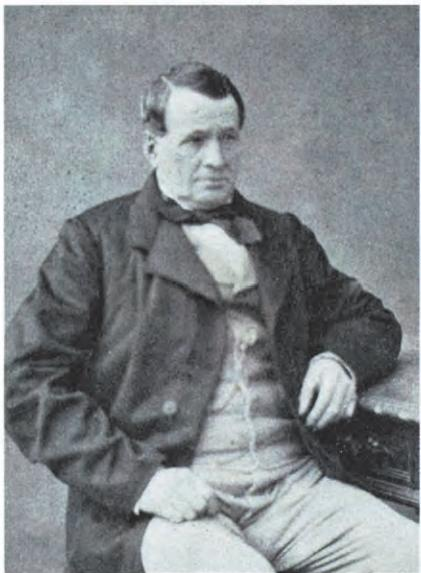 Black-and-white portrait of Thierry Hermès, the founder of Hermès. He is dressed in a 19th-century style coat, waistcoat, and bow tie, with a dignified posture.