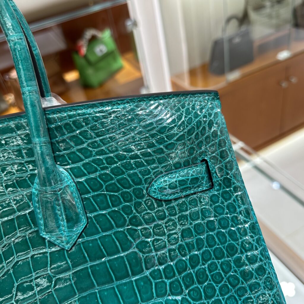 Macro view of authentic Cousu Sellier hand-stitching and symmetrical Porosus crocodile scales on a high-end Hermes Birkin replica.