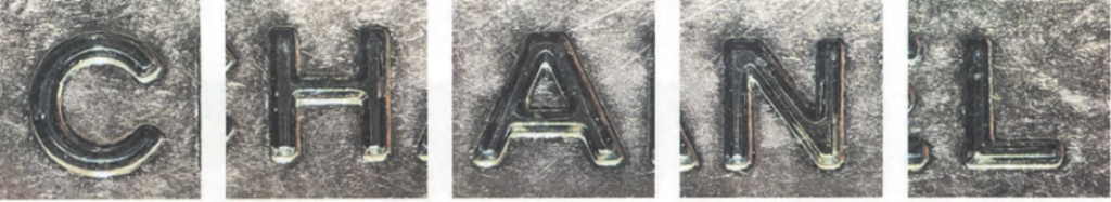 Authentic Chanel interior metal logo plate secured with standard flathead screws, a crucial detail to Chanel authenticate the bag's hardware.