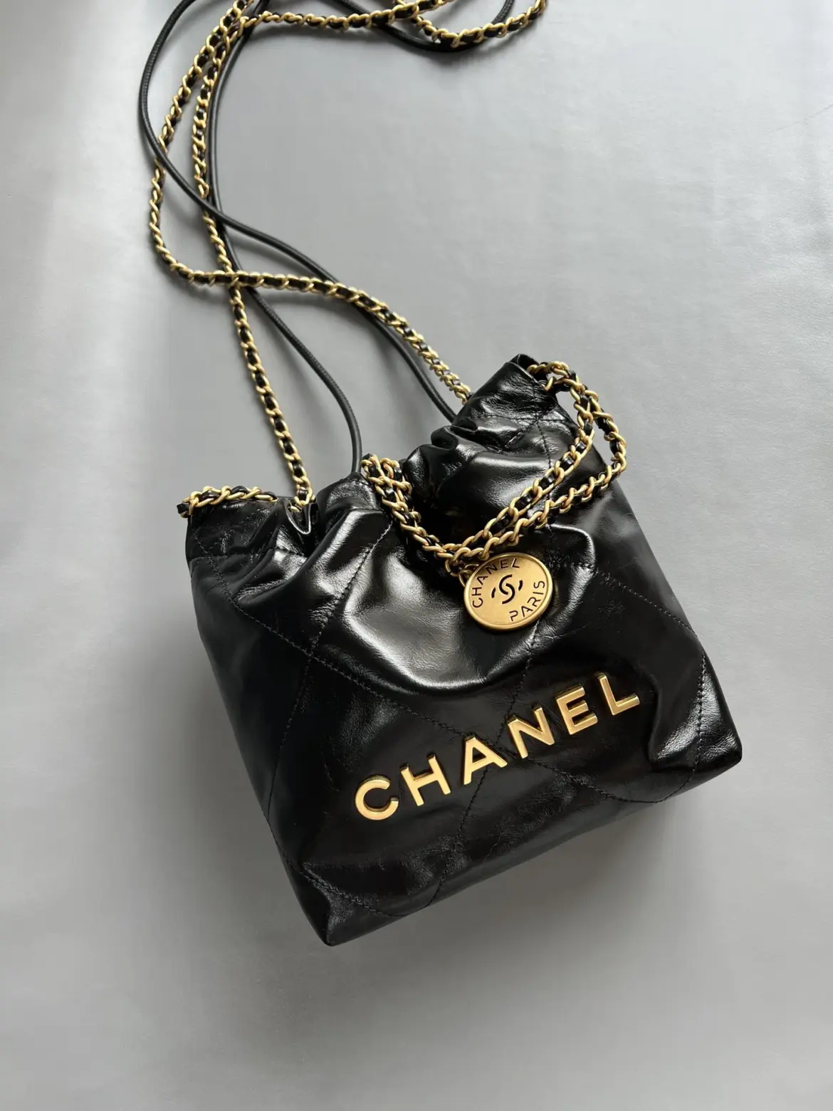 Chanel 22 Mini black gold replica shown from the front on a grey background