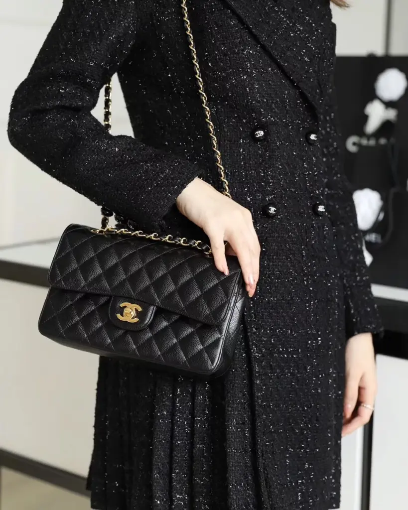 Chanel Classic Flap 25 black gold replica worn with a black tweed outfit