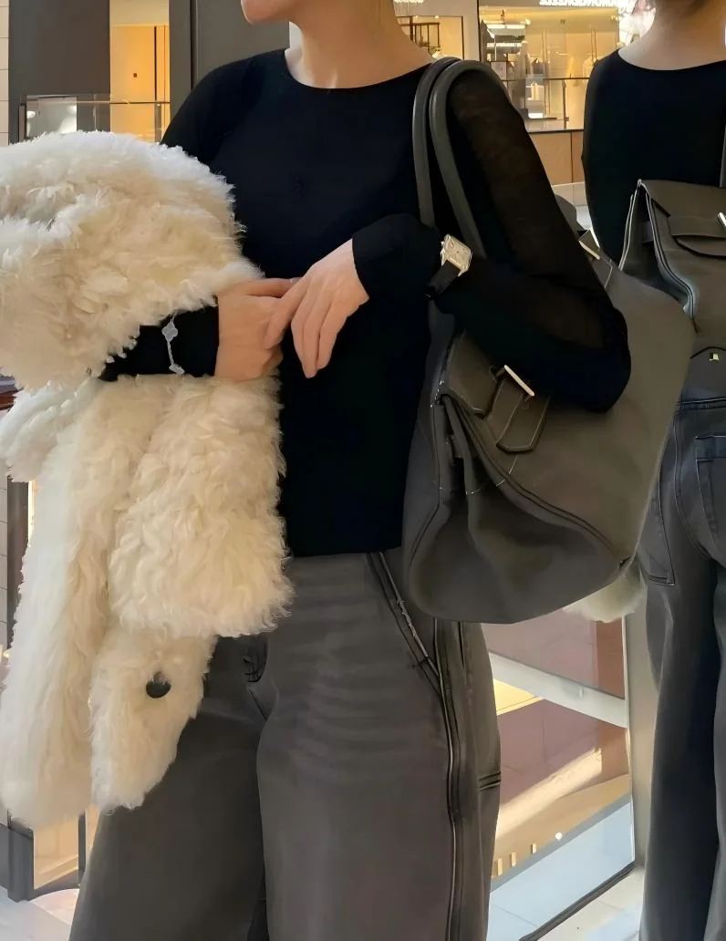 Close view of a black Shoulder Birkin 42 replica worn over the shoulder with a black top