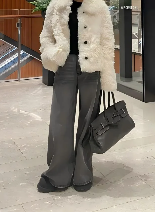 Full-body view of a black Shoulder Birkin 42 replica carried beside grey wide-leg trousers