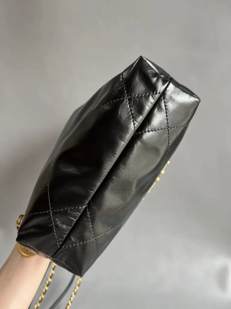Side and base profile of the black mini drawstring bag held in one hand