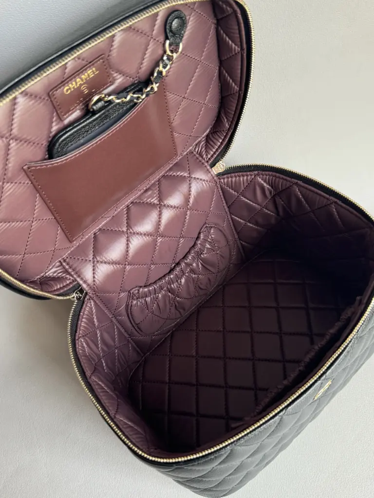 Open black vanity case with mauve quilted lining, slip pocket and small mirror