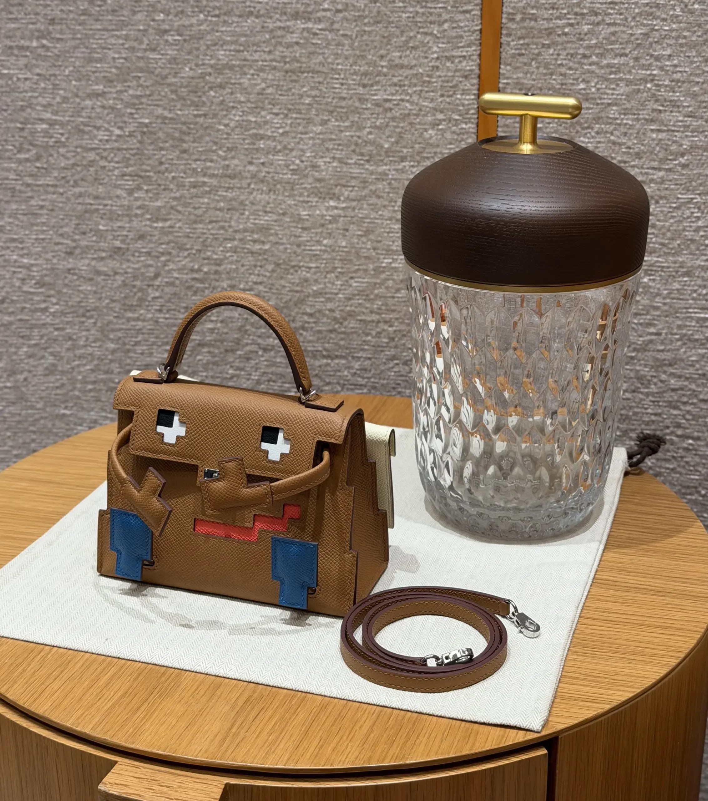 Gold Kellydoll Picto 16.5 replica beside a glass vessel with detachable strap