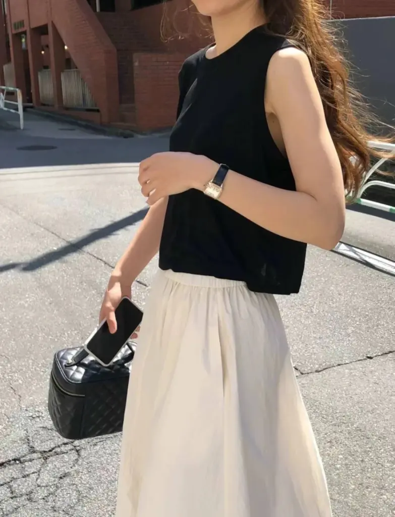 Chanel vanity case replica carried by hand with a black top and white skirt