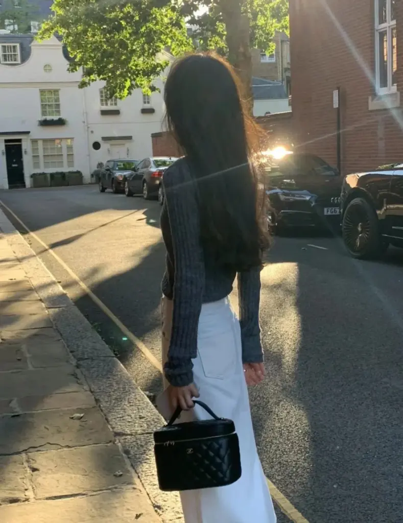 Black vanity case carried at sunset with a dark top and white skirt