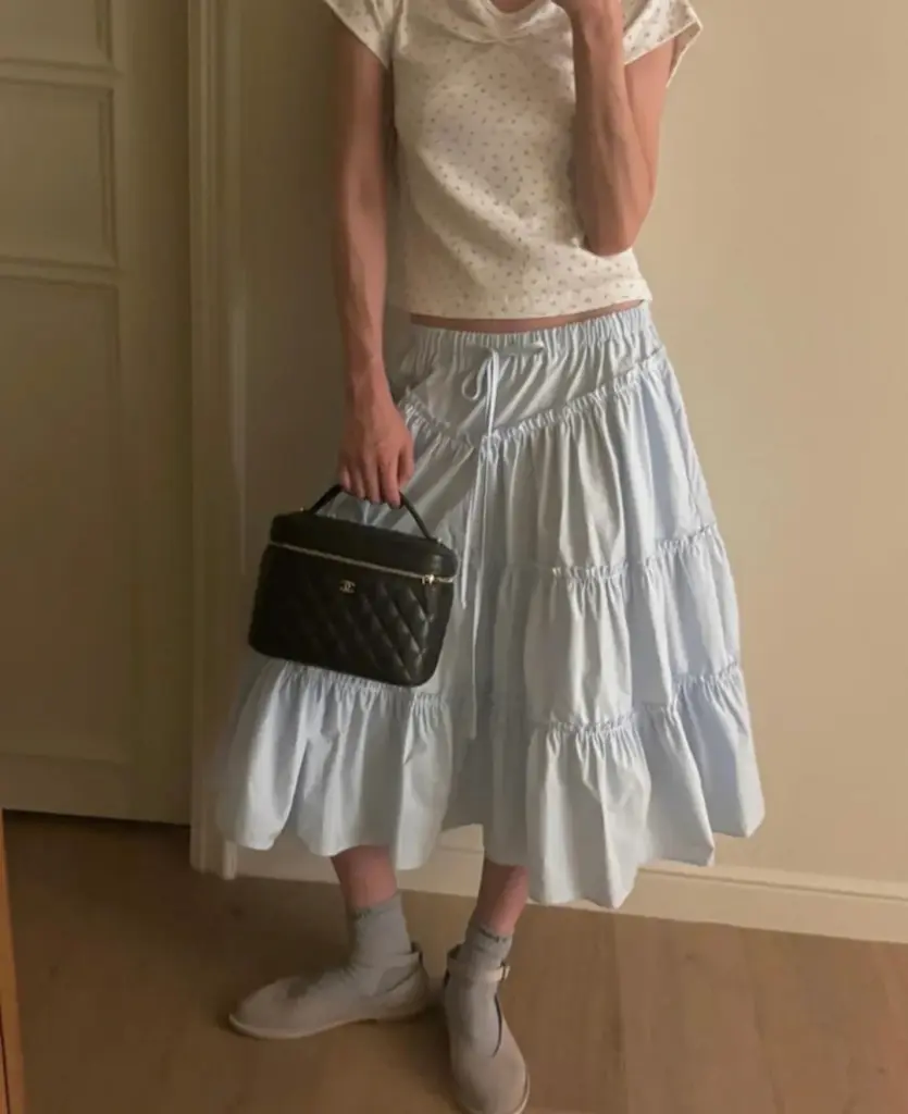 Black quilted vanity case styled indoors with a pale blue tiered skirt