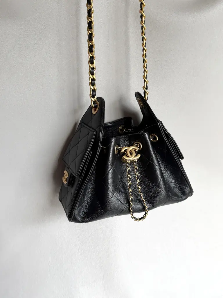 Hanging full view of a black Chanel 25 Mini-style bag with antique gold-tone chain