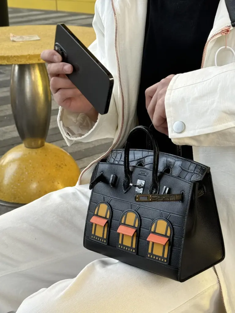 Dark Birkin 20 Faubourg replica resting against cream trousers in natural light