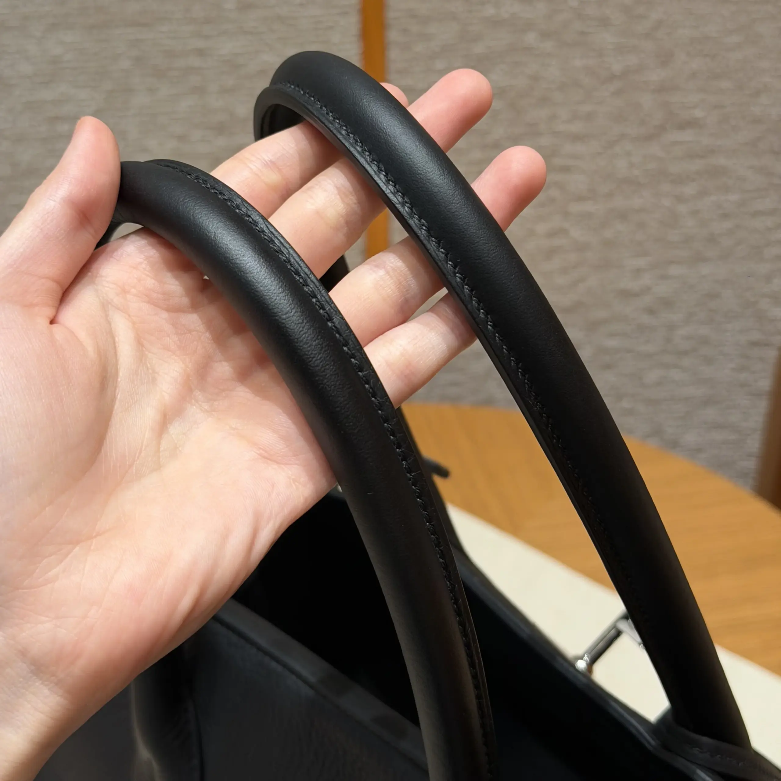 Macro view of the long black handles and stitching on a Shoulder Birkin 42 replica
