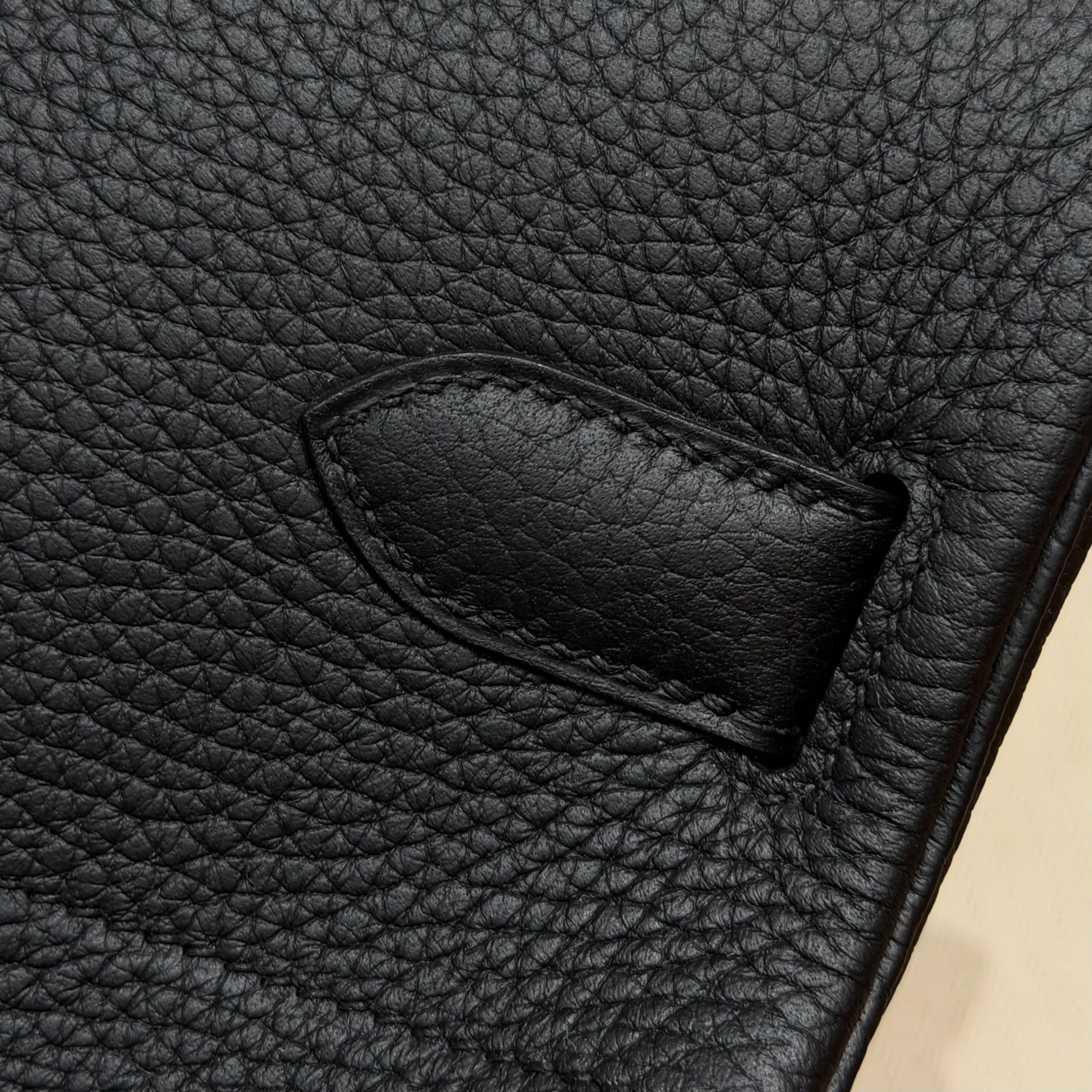 Macro view of a stitched black leather tab on the back of a Shoulder Birkin 42 replica