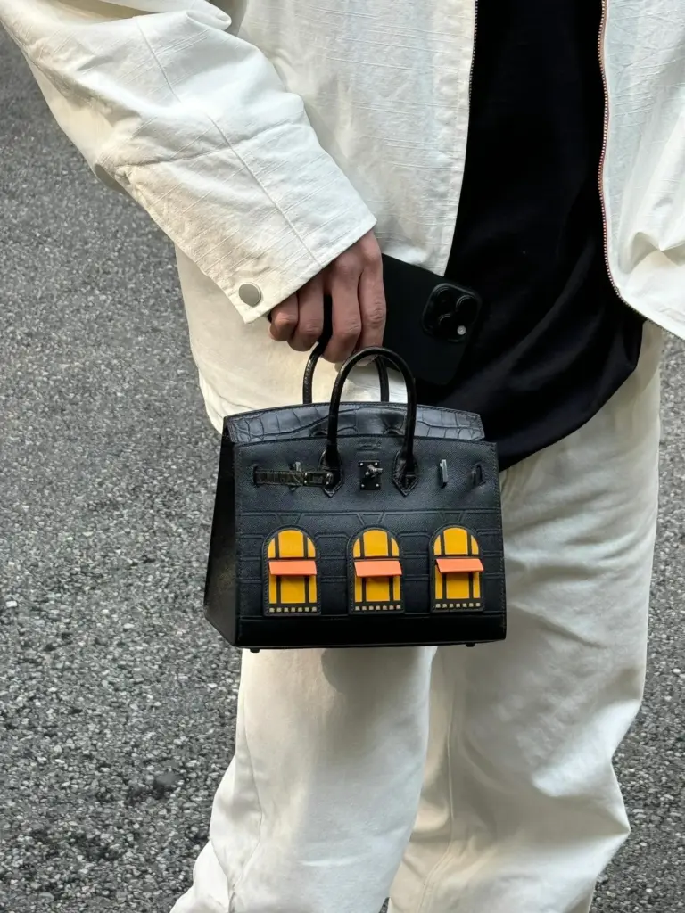 Front carry view of a Birkin 20 Faubourg replica against loose cream layers