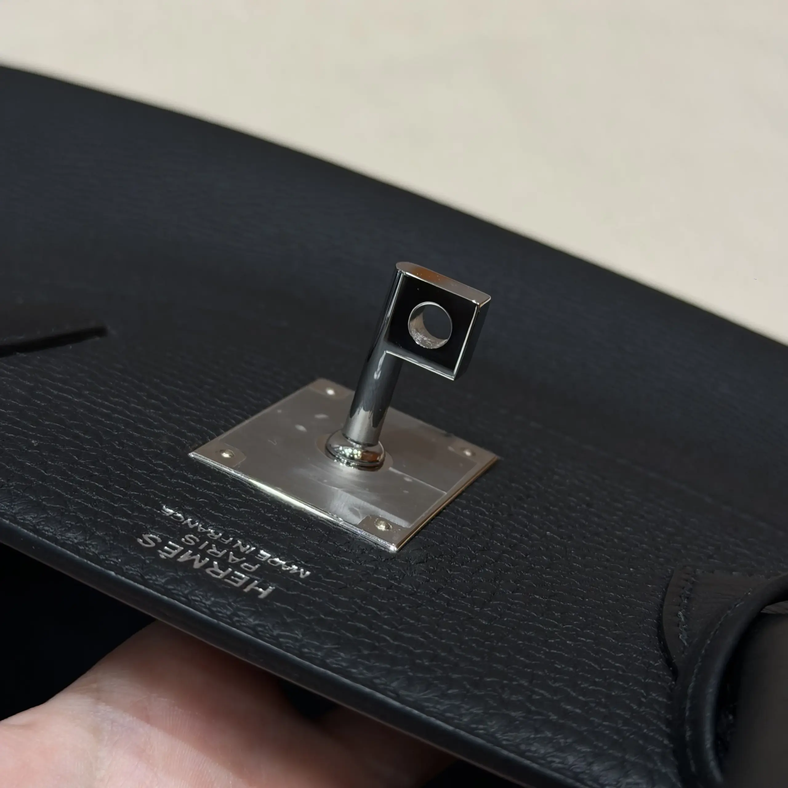 Macro view of the silver-tone turn-lock plate on a black Shoulder Birkin 42 replica