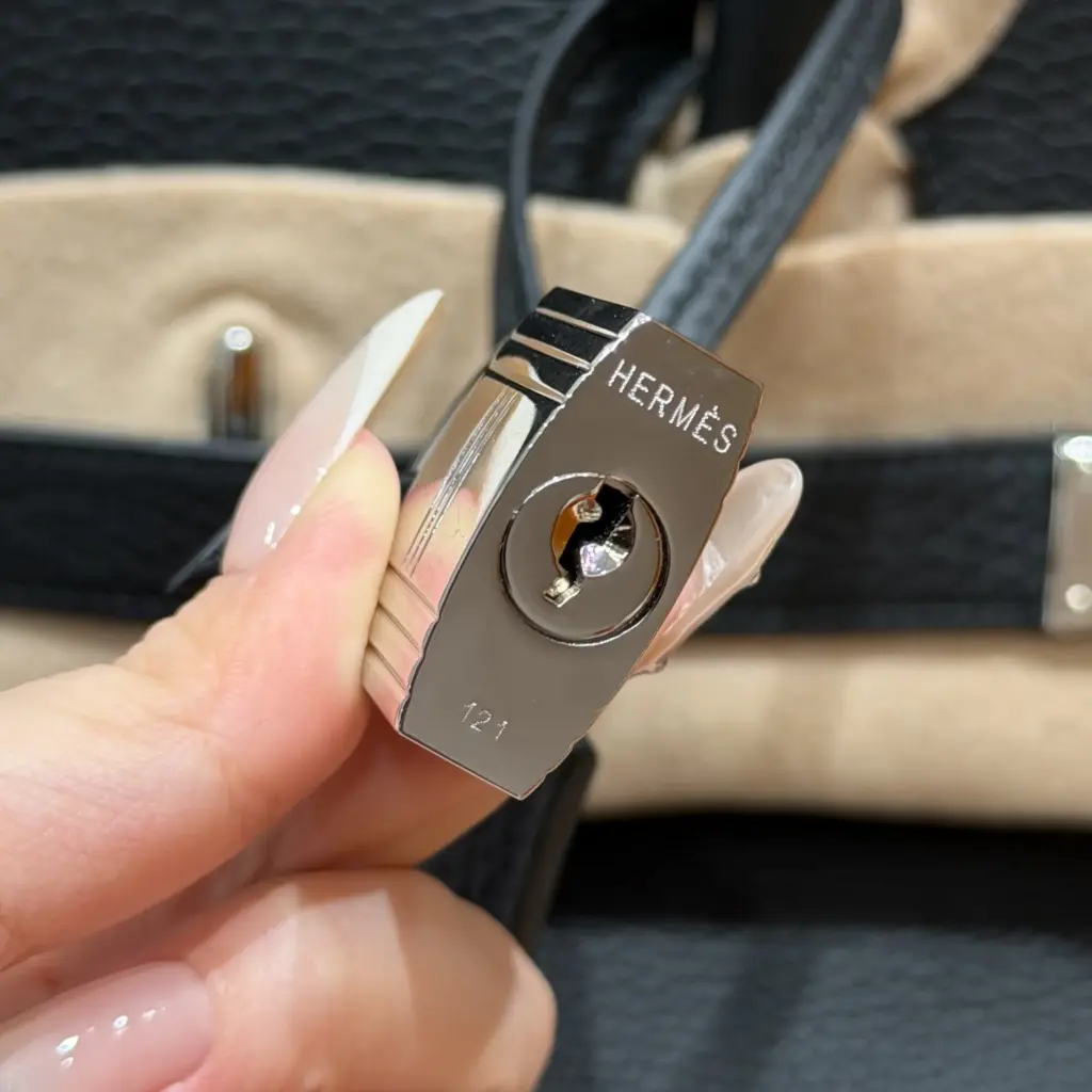 Macro view of the engraved silver-tone lock for a black Shoulder Birkin 42 replica
