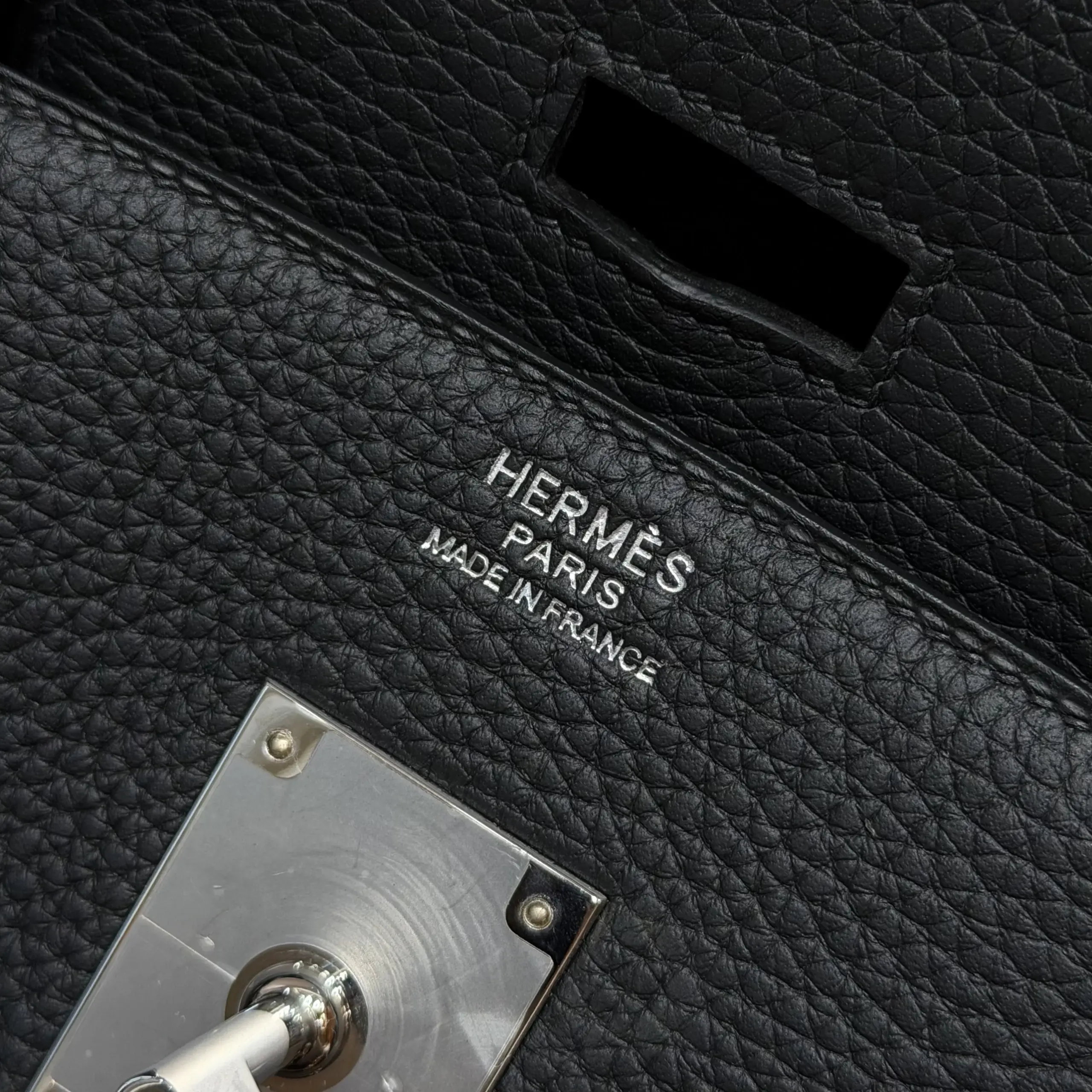 Macro view of the foil heat stamp and black pebbled leather on a Shoulder Birkin 42 replica