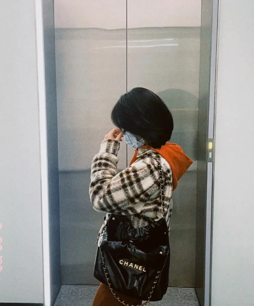 Styling reference showing a black Chanel 22-style bag worn on the shoulder