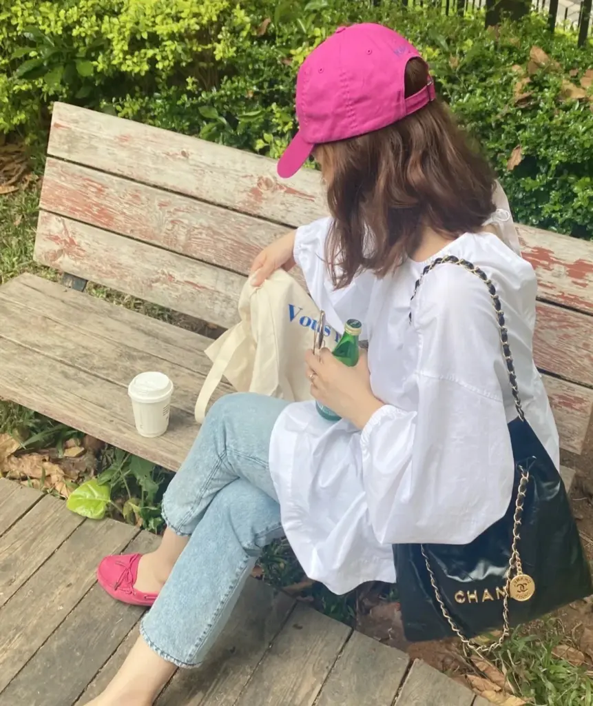Seated outdoor styling reference with a black and gold Chanel 22-style bag