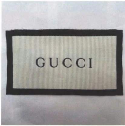 Front of a historical Gucci dust bag woven label with dark border and GUCCI lettering
