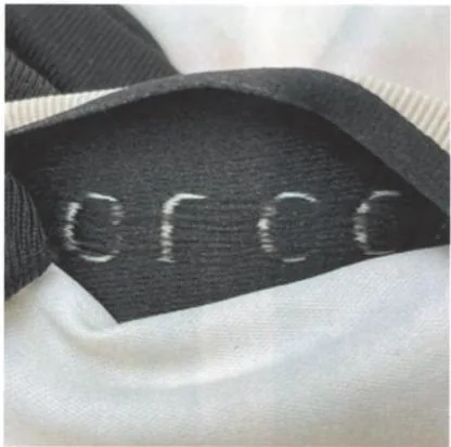 Reverse of a historical Gucci dust bag woven label showing dark backing yarns behind the lettering