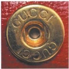 Gucci engraved snap fastener photographed against red leather