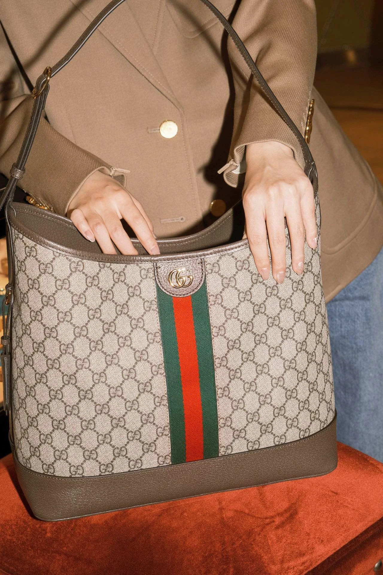 Monogram shoulder bag held open in front of a taupe blazer
