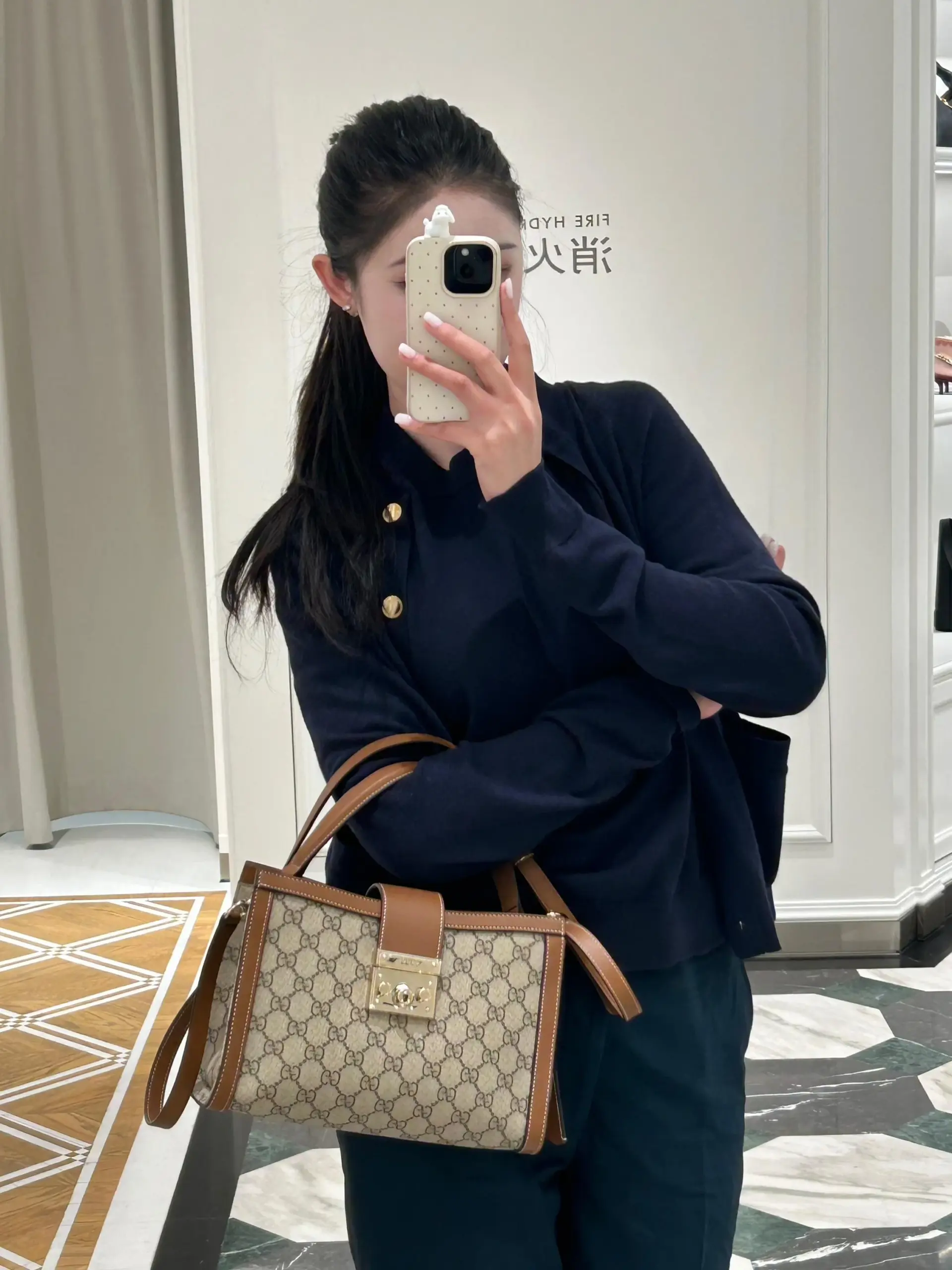 Gucci Padlock held by its short handle against a navy outfit