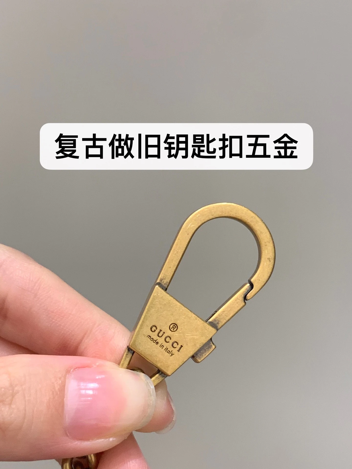 Aged gold-tone key clasp with engraved lettering and a visible spring gate