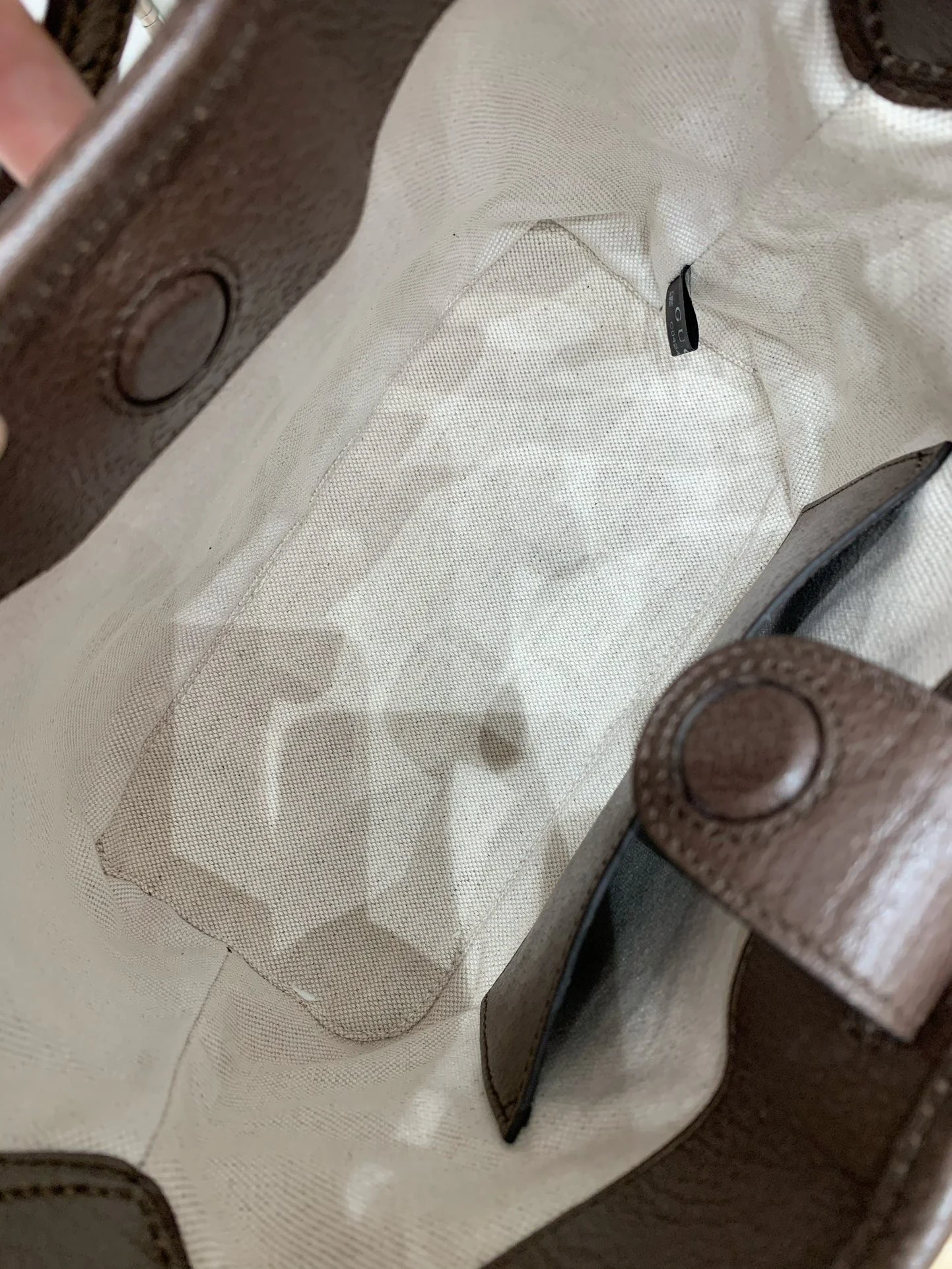 Light woven lining and brown closure tabs inside the bag