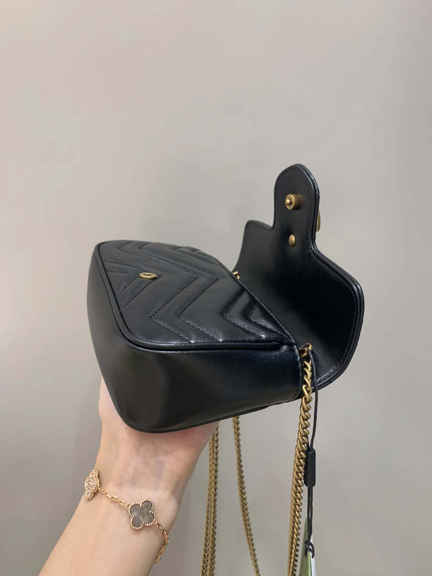 GG Marmont with its flap raised, exposing a curved corner and chain attachment