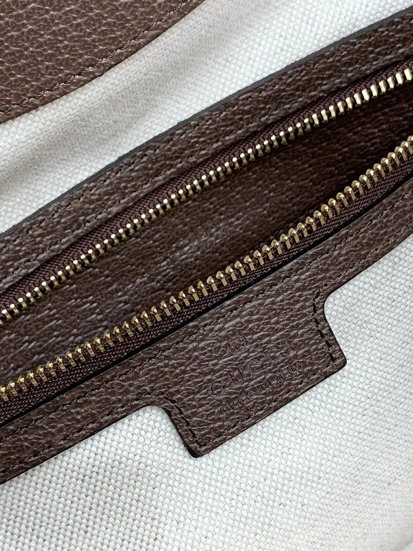 Gold-tone zipper teeth and an embossed brown interior label