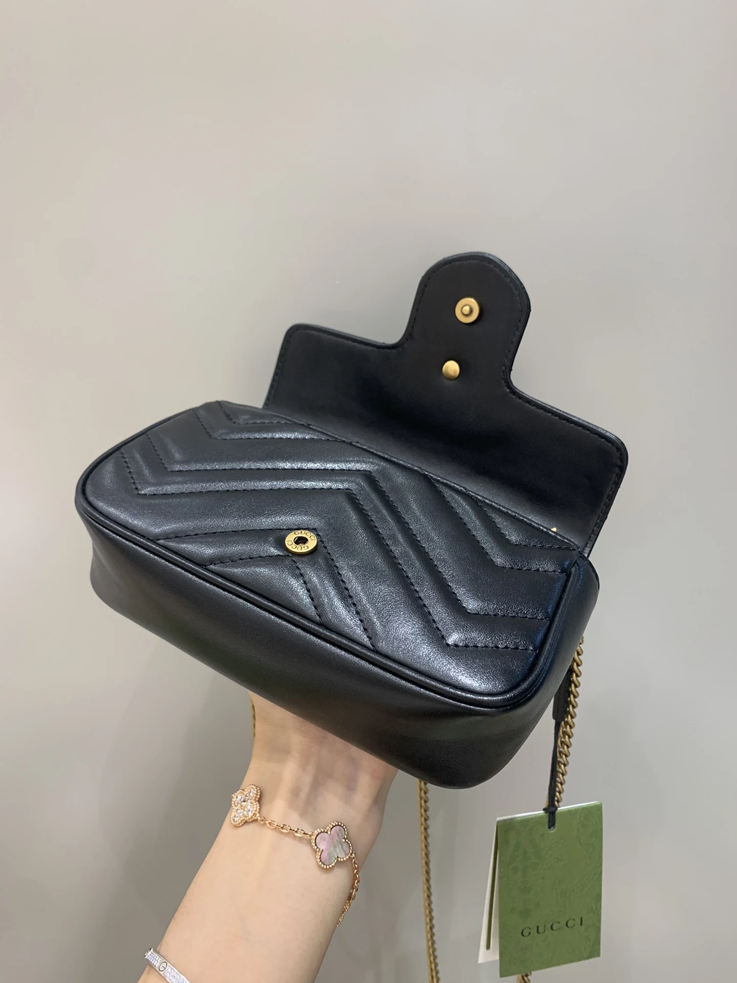 Gucci GG Marmont black-and-gold replica held open to reveal chevron quilting and its smooth base